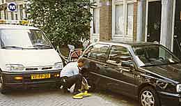 An Amsterdam police officer places a wheel clamp on an illegally parked car.