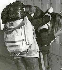 Two backpackers struggle to get their loads on their backs at the Munich, Germany train station.