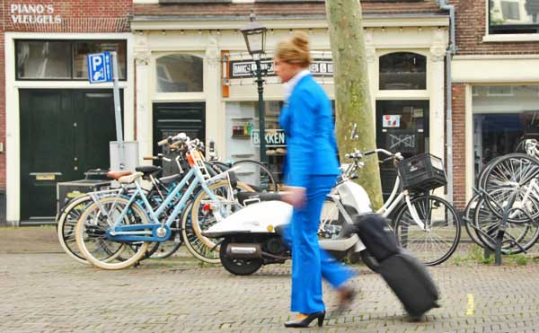 A KLM flight attendent with rolling bag and hand bag going to Amsterdam's Schiphol Airport.